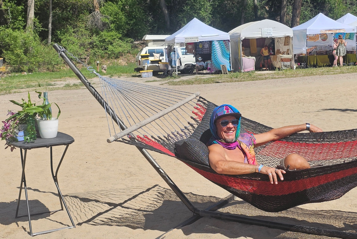 Model lounging in the Rainbow Paisley poncho scarf at a festival