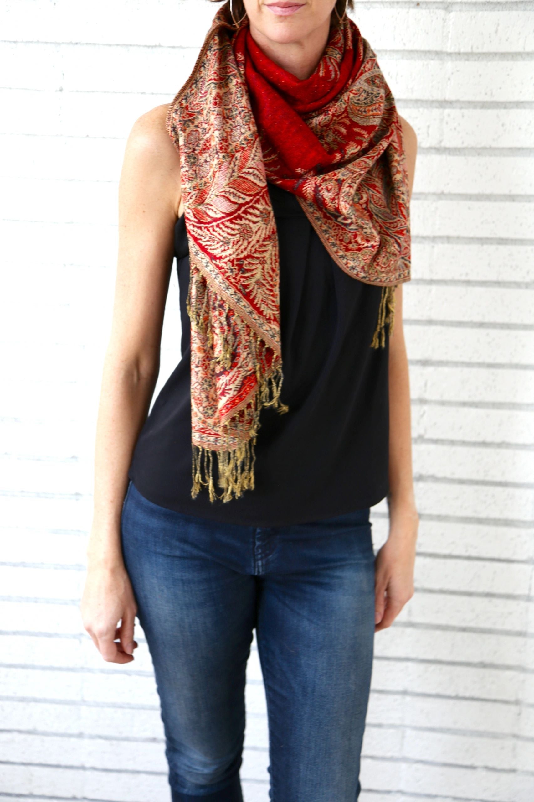 Red paisley poncho scarf with gold fringe, shown on a model
