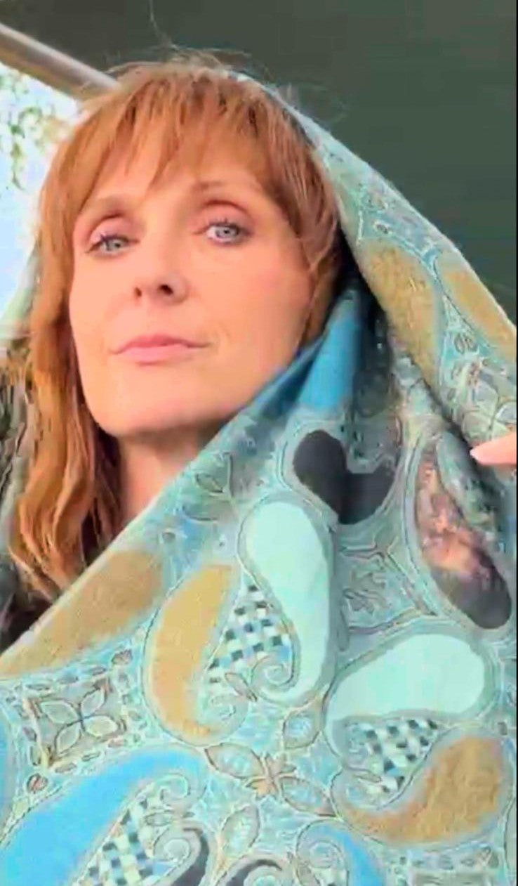 Model pulling the turquoise Large Paisley poncho scarf over her head