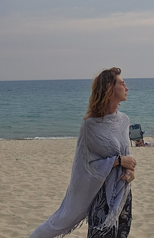 Lightweight poncho scarf worn over a swimsuit by the water