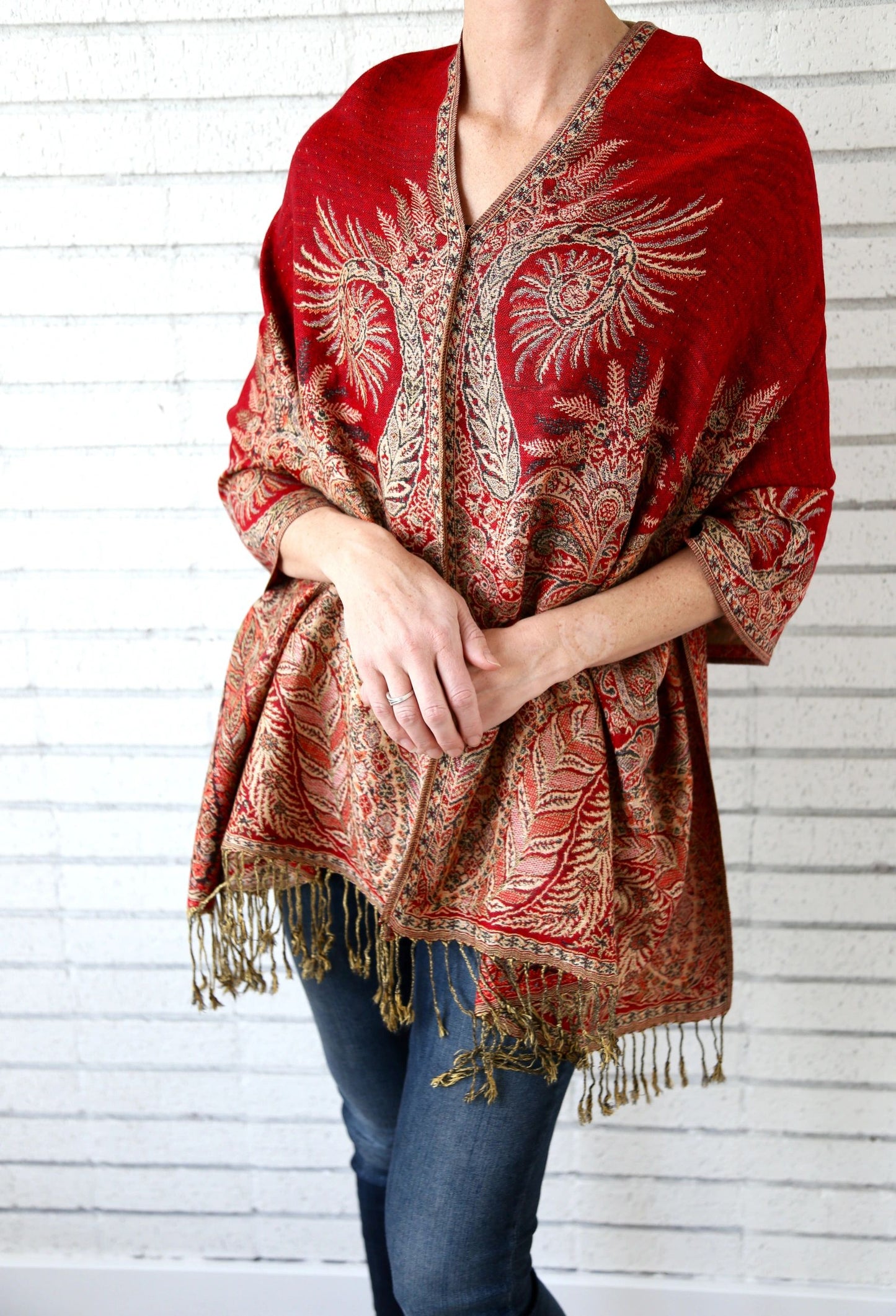 Red paisley poncho scarf worn with the seam at the front, over jeans