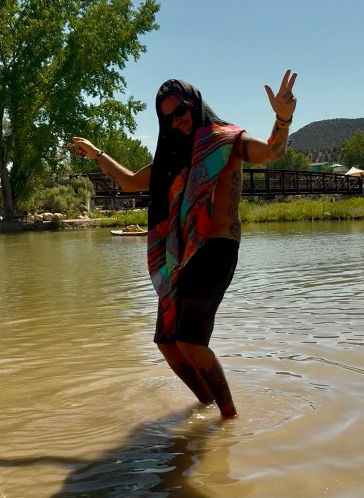 Striped poncho scarf worn as a head wrap by the river